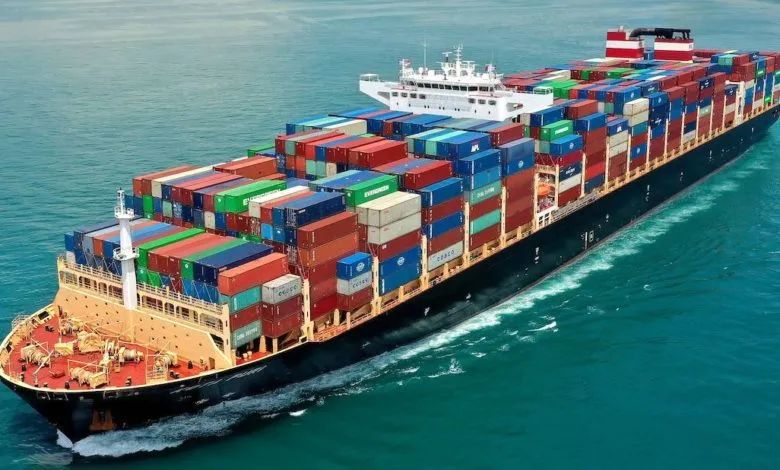 The ship is a large container vessel, with multiple stacks of colorful shipping containers loaded on the deck. Cargo Ship in ocean